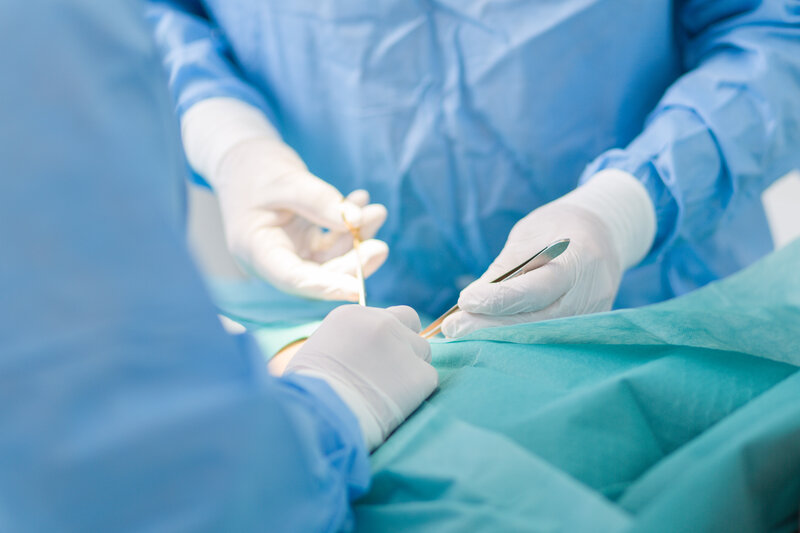 医師が手術用メスを持ち、患者の鼻部位に対して施術を行っている場面