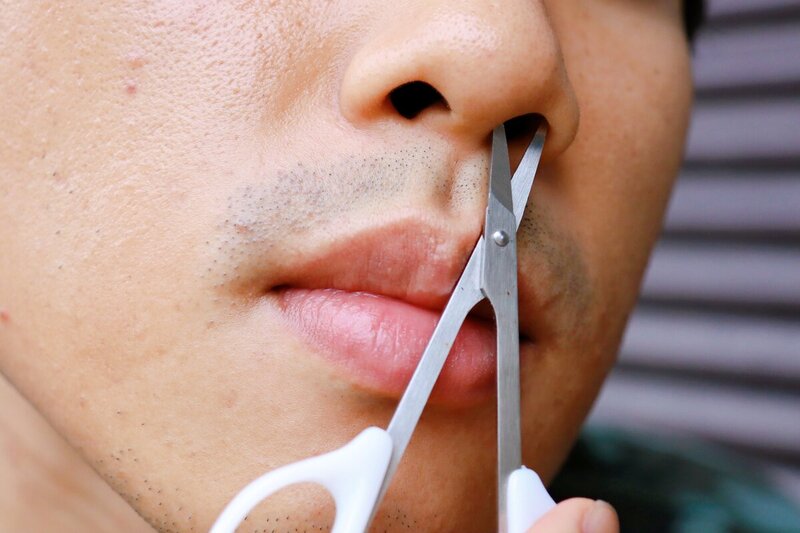 男性の横顔で鼻毛を処理している施術シーン
