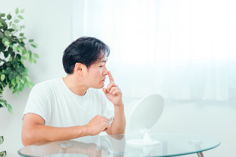 鼻に指を当てて考える男性の横顔